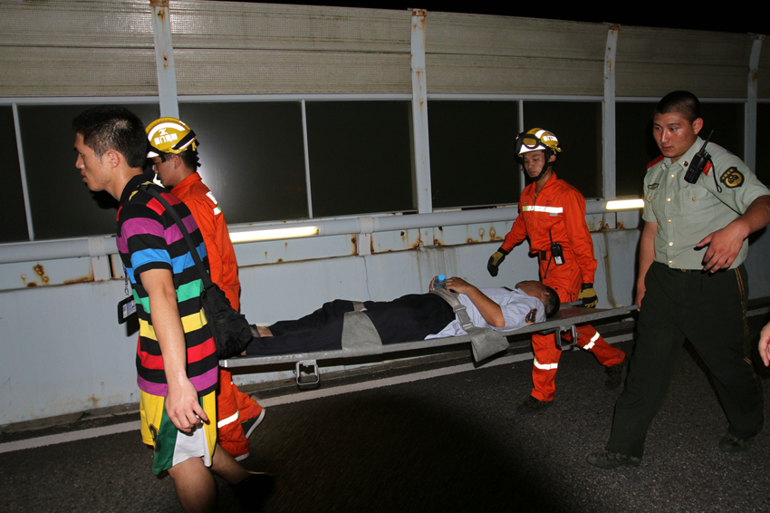 Photo taken on June 7, 2013 shows rescuers carry an injured man from the bus on fire on an elevated track in Xiamen, southeast China's Fujian Province. At least 48 people died and more than 30 others were injured after the bus in the city's BRT (bus rapid transit) service burst into flames at about 6:30 p.m. on Friday. [Photo/Xinhua]