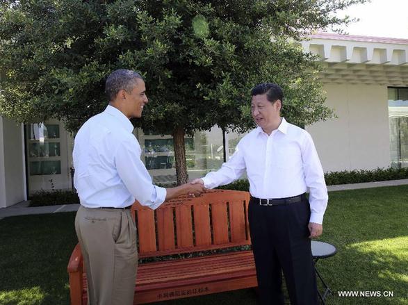 U.S. President Barack Obama (L) presents Chinese President Xi Jinping with a bench made of California redwood while they take a joint walk before heading into their second meeting, at the Annenberg Retreat, California, the United States, June 8, 2013. Chinese President Xi Jinping and U.S. President Barack Obama held the second meeting here on Saturday to exchange views on economic ties. [Lan Hongguang/Xinhua]