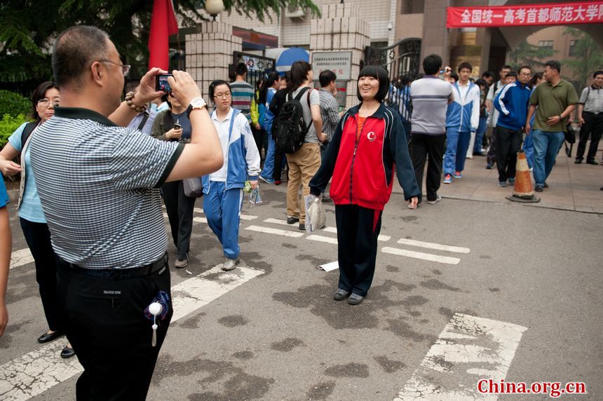 A girl student is posing for photos taken by her father after she finishes the college examination on Saturday, June 8, 2013 in Beijing. [Photo / Chen Boyuan]