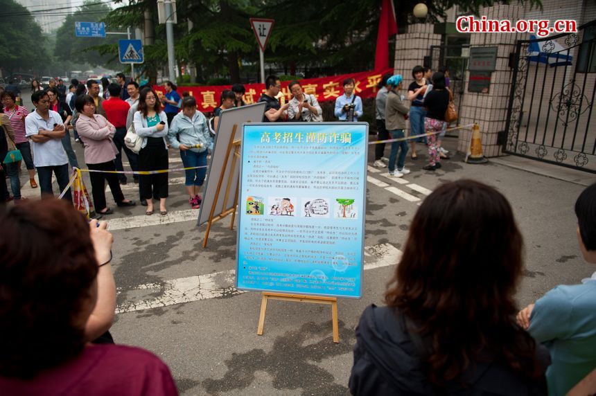 A sign that warns students&apos; parents of the risk and fraud in college adimission is posted outside the school gate of High School Attached to Capital Normal University on Saturday afternoon as the anxious parents are waiting outside for their children to finish the examination. China&apos;s 2013 national college entrance examination ends on Saturday, June 8, 2013. [Photo / Chen Boyuan]