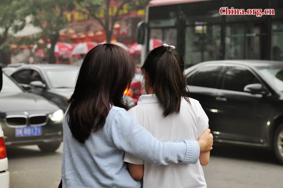 A student is discussing with her awaiting family member after she finishes this year&apos;s national college entrance examination on Saturday afternoon, June 8, 2013. A total of 72, 736 students in Beijing have registered to sit this &apos;big test.&apos; [Photo / Gong Yingchun]