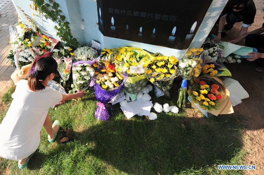 A woman lays flowers to mourn for the victims in front a pier of the elevated bus lane where a bus fire took place on Friday, in Xiamen, southeast China&apos;s Fujian Province, June 8, 2013. The bus fire has claimed 47 lives and hospitalized 34 passgengers.