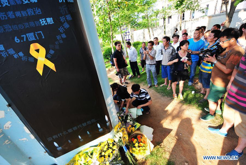 People lays flowers to mourn for the victims in front a pier of the elevated bus lane where a bus fire took place on Friday, in Xiamen, southeast China&apos;s Fujian Province, June 8, 2013. The bus fire has claimed 47 lives and hospitalized 34 passgengers.