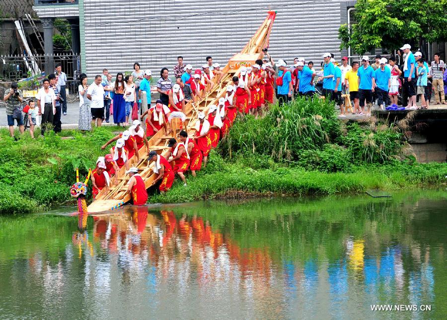 Participants push a boat into water for a boat race held to mark the annual Dragon Boat Festival in Sanxi Village, Jiangtian Town, Changle, southeast China&apos;s Fujian Province, June 10, 2013. This year&apos;s Dragon Boat Festival falls on June 12. (Xinhua/Zhang Bin)