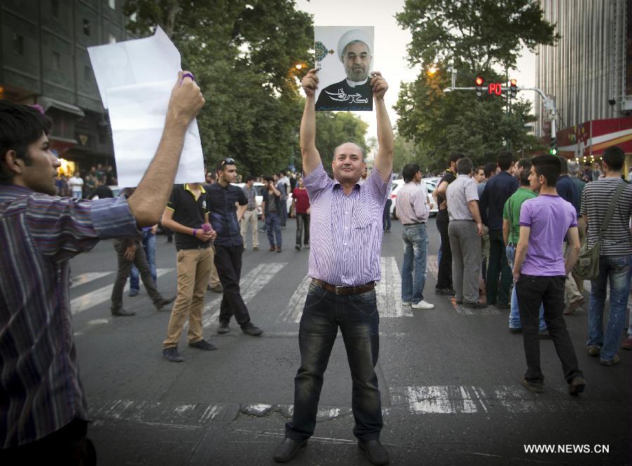 A man holds a poster of Iran's former nuclear negotiator Hassan Rouhani to celebrate his victory at the presidential election on a street in Tehran, Iran, June 15, 2013. Hassan Rouhani defeated his rival conservative candidates in Iran's 2013 presidential election Saturday by gaining 18,613,329 votes out of counted votes of 36,704,156, accounting for 50.7 percent of all the votes, with a turnout rate of 72.2 percent. [Ahmad Halabisaz/Xinhua]