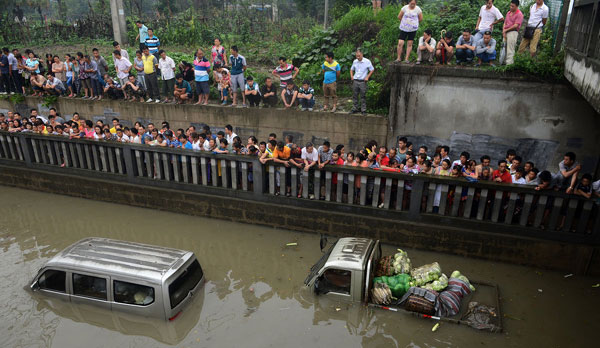 Heavy rainfall traps a van and a truck as a crowd of people observe in Chengdu, Southwest China's Sichuan province on June 20, 2013. [Photo/Xinhua]