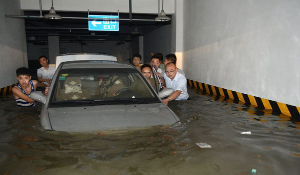 People push flooded cars out of a garage in Chengdu, Southwest China's Sichuan province on June 20, 2013. [Photo/Xinhua] 