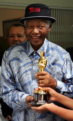 Former South African President Nelson Mandela poses with the Oscar awarded to the film &apos;Tsotsi&apos; at his home in Cape Town, March 16, 2006. &apos;Tsotsi&apos; won for Best Foreign Film and is the first South African film to receive the award.[Xinhua]