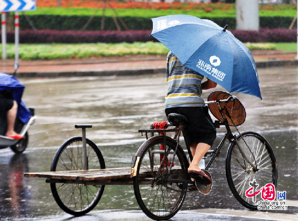 2013年6月22日，海南琼海市民在大雨中出行。今年第5号热带风暴“贝碧嘉” 即将于22日下午在海南万宁到广东湛江一带沿海地区登陆。