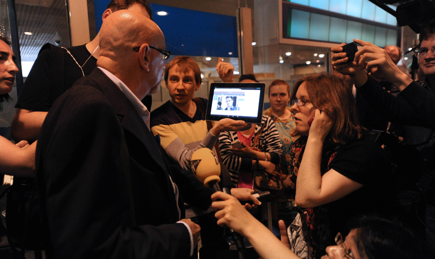 A journalist shows to a passenger a picture of former US spy Edward Snowden on a tablet, at the arrival gate of the Moscow Sheremetevo airport on June 23, 2013. 