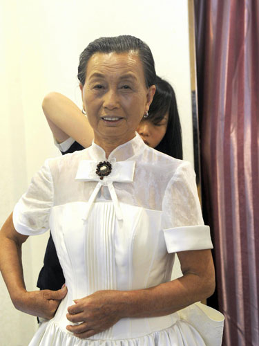 A woman tries on a wedding dress at a photography studio in Hefei, East China's Anhui province, July 4, 2013. A community in Hefei and Hefei University of Technology offered free wedding photos for 11 couples over the age of 60. The oldest couple were 80 years old. [Photo/Xinhua] 