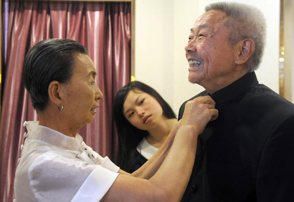 A woman adjusts her husband's suit before sitting for free wedding photos, in Hefei, July 4, 2013. [Photo/Xinhua]