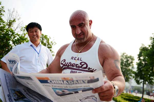 A contestant in the 2013 China World Strongman Championship reads China Daily on Sunday. Photo by Xiang Mingchao 