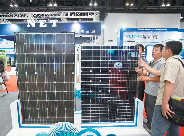 Visitors look at solar panels at the Clean Energy Expo China in Beijing on July 3. Ten of 22 listed solar panel companies have released interim statements indicating a recovery based on expansion in new markets and the domestic market. 