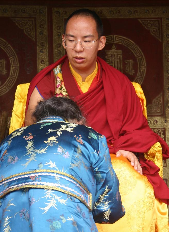 The 11th Panchen Lama Bainqen Erdini Qoigyijabu gives blessing to a devotee at the Taer Monastery in Huangzhong County, northwest China's Qinghai Province, July 2, 2013. [Photo/Xinhua]