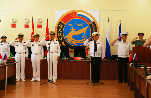 Chinese and Russian navy officers salute their national flags during the closing ceremony of the China-Russia 'Joint Sea 2013' naval exercises on Thursday in Vladivostok, Russia. [Photo/Xinhua]
