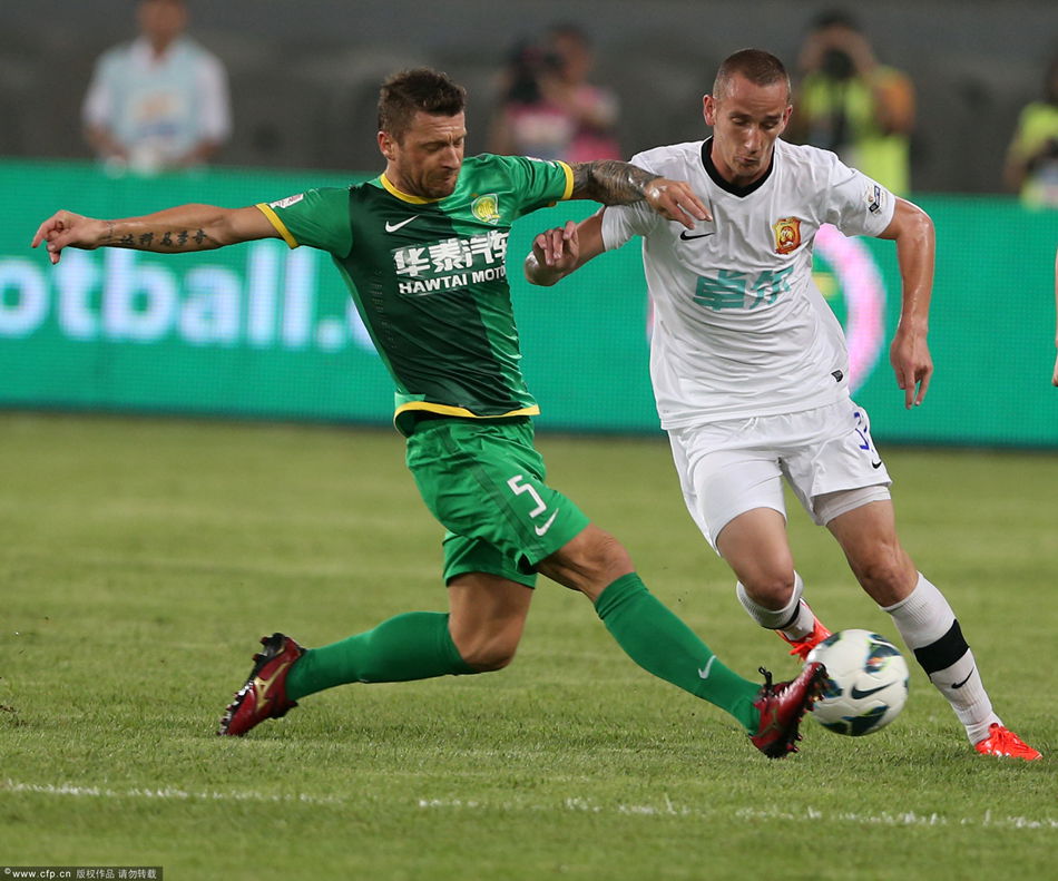 Darko Matic of Beijing Guoan tries to stop Wuhan's Milos Stojanovic.