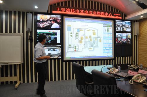Staying alert: A staff member at Dayawan introduces how the power plant's emergency center works.[Photo/Beijing Review]