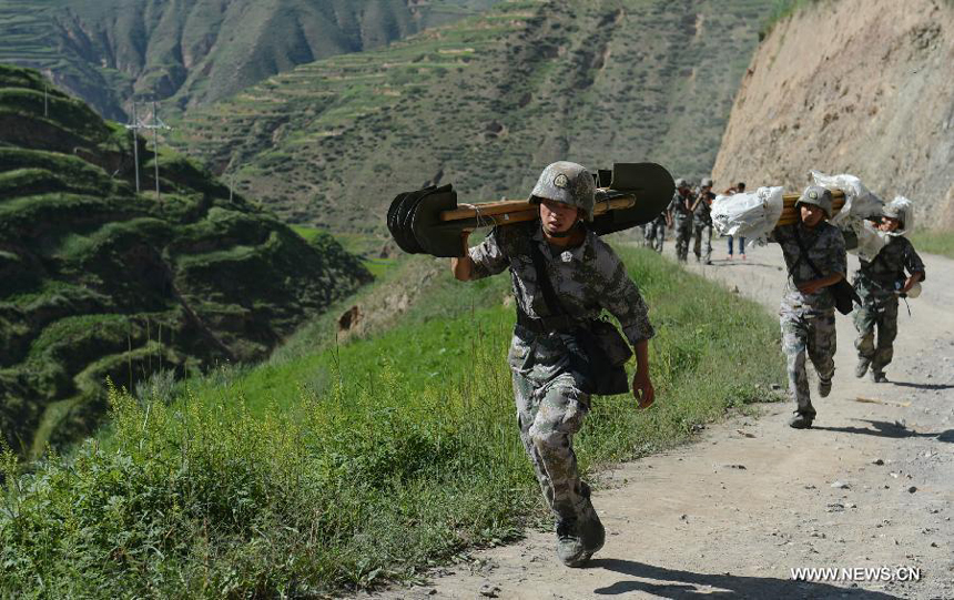 Rescuers carry relief supplies to Yongguang Village of Meichuan Town in Minxian County, northwest China's Gansu Province, July 22, 2013. The death toll has climbed to 89 in the 6.6-magnitude earthquake which jolted a juncture region of Minxian County and Zhangxian County in Dingxi City Monday morning. 