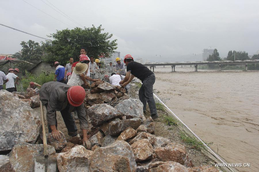 Residents reinforce the riverbank of the Dong River in Chengxian County of Longnan City, northwest China&apos;s Gansu Province, July 25, 2013. A torrential rain battered Chengxian County Wednesday night, causing landslips, collapses and traffic disrupted. A total of 1,060 residents have been evacuated by now. 