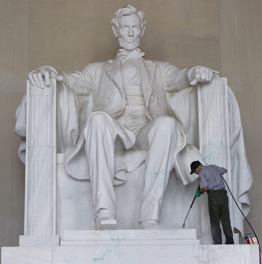 A worker with the National Park Service cleans off paint thrown on the Lincoln Memorial overnight by vandals on the National Mall in Washington, DC, July 26, 2013. 