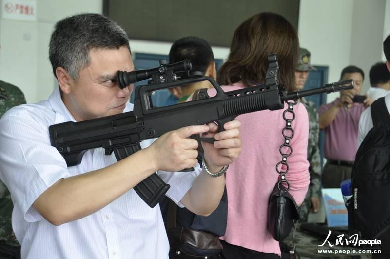 A journalist takes aim with a PLA rifle on display. [Photo/people.com.cn]