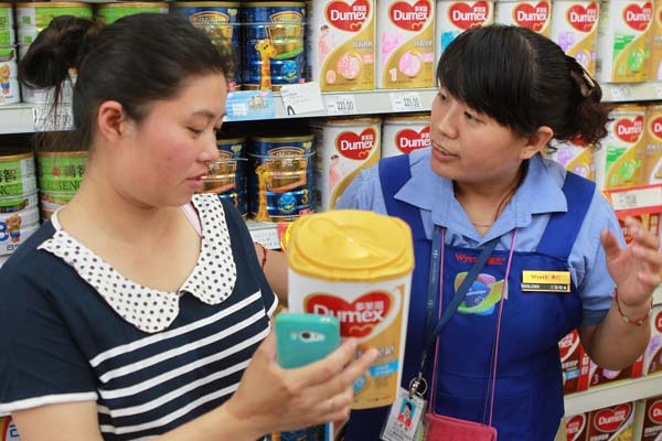 Mu Liping (left) checks with a saleswoman at a supermarket in Beijing on Sunday whether her newly bought Dumex baby formula should be recalled. Dumex announced it was recalling 12 batches of products in China that may be contaminated. Mu found her purchase didn't belong to the recalled batches and left with the baby power.