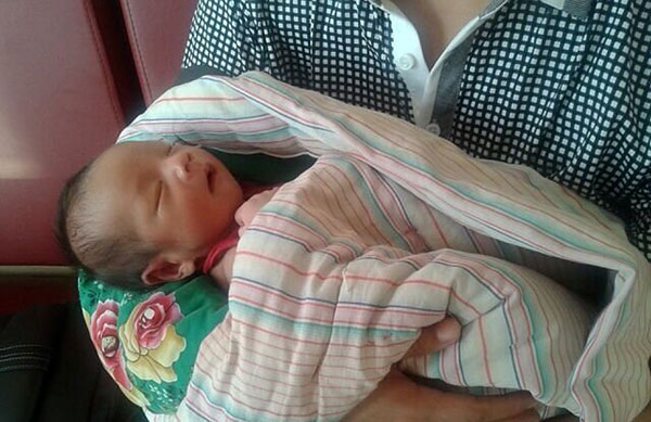 A baby rescued by police from an infant trafficking in central China's Henan province is safe with his parents at the Fuping County Maternal and Child Health Care Hospital in Fuping, Shaanxi province, on Aug 4, 2013. [Photo/Xinhua]