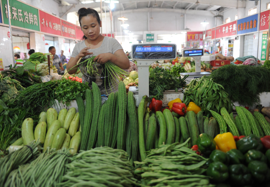 A seller arranges vegetables at a market in Shijiazhuang, capital of north China's Hebei Province, Aug. 9, 2013. China's consumer price index (CPI), a main gauge of inflation, grew 2.7 percent year on year in July, staying flat from the figure for June, the National Bureau of Statistics (NBS) announced on Friday. 