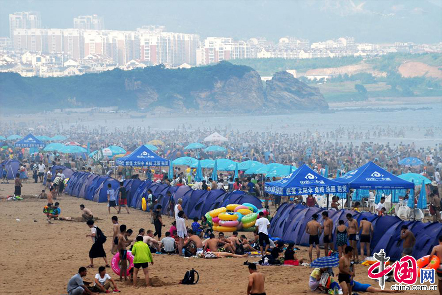 8月11日，青岛持续的高温天气，使海边成了热点旅游地区。当日下午，石老人风景区游人如潮，进入秋季以来，沿海地区“高烧”不退，闷热天气仍未缓解，游客海边扎堆下水，避暑纳凉场面壮观。图为彩色的帐篷，密集的人群，人们扎堆“下饺子”现场。[中国网图片库 王海滨 摄]