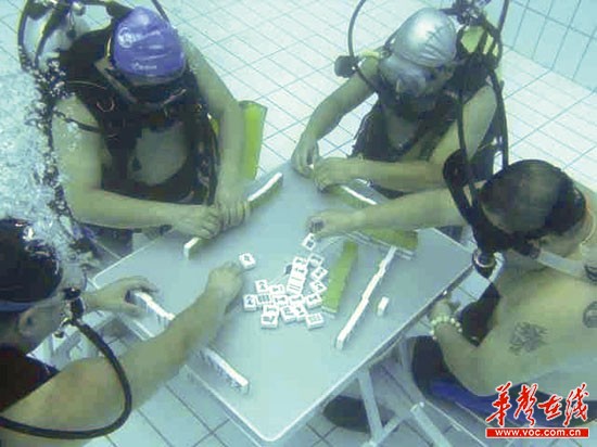 Divers are seen playing mahjong at the bottom of a swimming pool in Xiangtan city, central China's Hunan Province on August 9, 2013. [Photo: xtol.cn]
