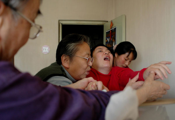 The paralyzed Zhu Ling (second right) tries to move with the help of her parents and a housemaid. Zhu was poisoned with thallium 19 years ago when she was studying at Tsinghua University in Beijing. The case has never been solved. [Photo/China Daily] 