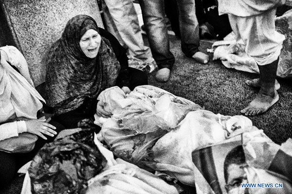 A woman cries beside a dead body at a mosque where lines of bodies wrapped in shrouds were laid out in Cairo, Egypt, Aug. 15, 2013. 