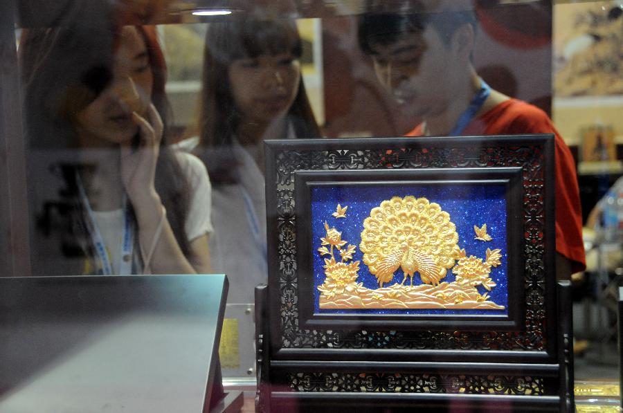 Visitors watch the displayed golden products during the 28th China Beijing International Gifts, Premium and Houseware Exhibition in Beijing, capital of China, Aug 14, 2013. The four-day exhibition, with the participation of 1,500 exhibitors from both home and abroad, opened on Wednesday. [Photo/Xinhua]