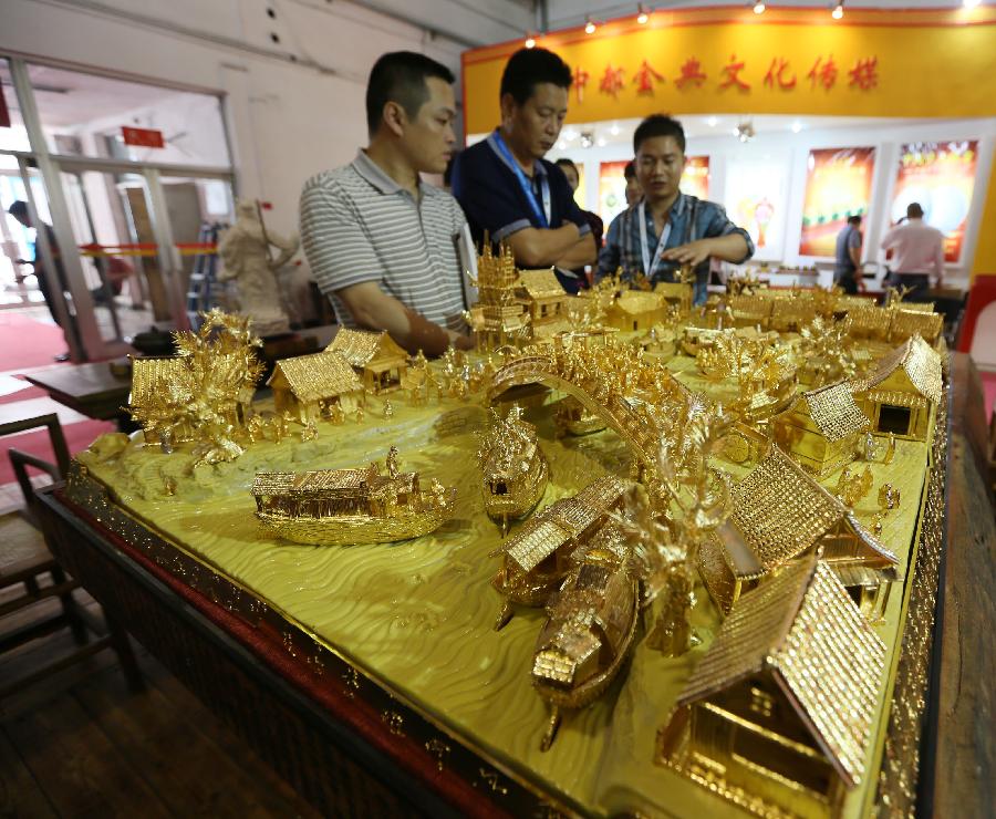 Visitors watch the displayed golden products during the 28th China Beijing International Gifts, Premium and Houseware Exhibition in Beijing, capital of China, Aug 14, 2013. The four-day exhibition, with the participation of 1,500 exhibitors from both home and abroad, opened on Wednesday. [Photo/Xinhua]