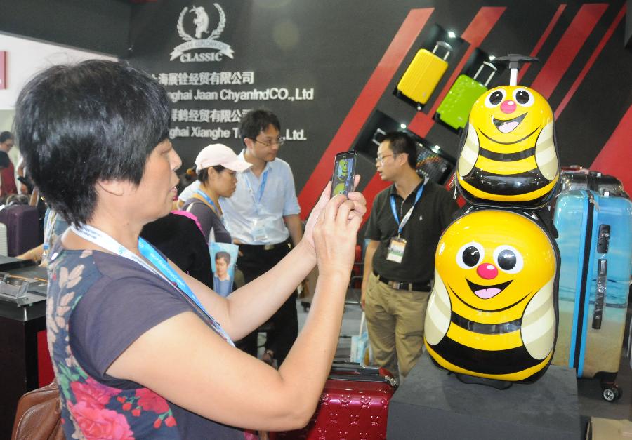 Visitors watch the displayed golden products during the 28th China Beijing International Gifts, Premium and Houseware Exhibition in Beijing, capital of China, Aug 14, 2013. The four-day exhibition, with the participation of 1,500 exhibitors from both home and abroad, opened on Wednesday. [Photo/Xinhua] 