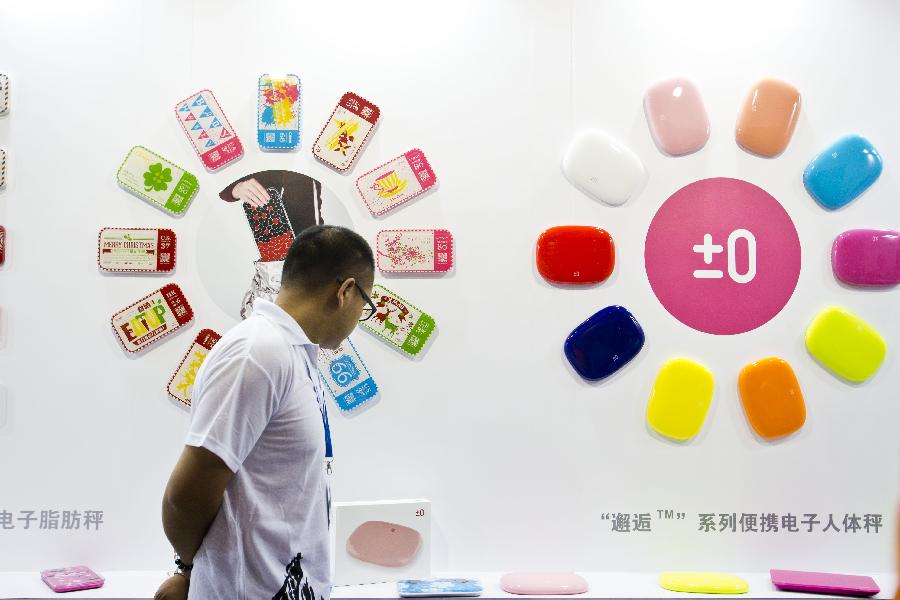 A visitor watches portable electronic scales during the 28th China Beijing International Gifts, Premium and Houseware Exhibition in Beijing, capital of China, Aug 14, 2013. The four-day exhibition, with the participation of 1,500 exhibitors from both home and abroad, opened on Wednesday. [Photo/Xinhua]