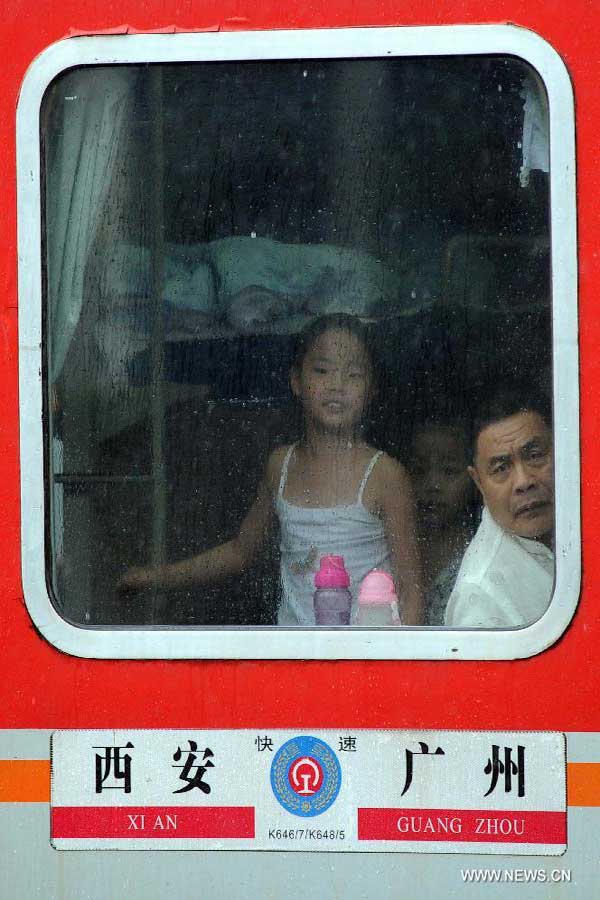 Passengers are seen through a window of a train stranded in the Guangzhou Railway Station in Guangzhou, capital of south China's Guangdong Province, Aug. 18, 2013. 