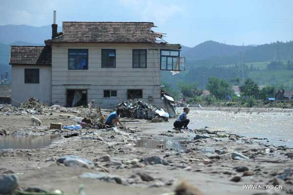 Local residents wash clothes by a river in flood-battered Nankouqian County, Fushun City of northeast China's Liaoning Province, Aug. 18, 2013.[Xinhua]