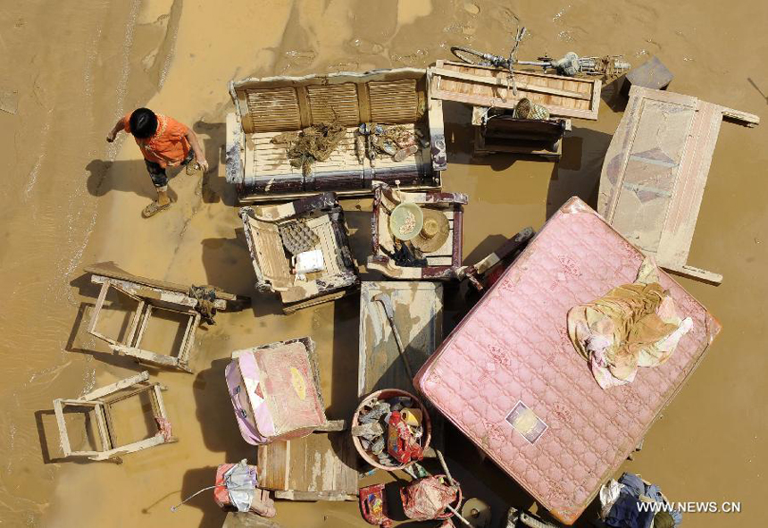 A woman sorts out flooded furniture in Yangtou Village of Zijin County in Heyuan City, south China&apos;s Guangdong Province, Aug. 