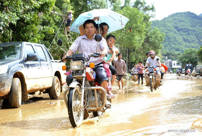 Villagers ride on a road covered with silt in Yangtou Village of Zijin County in Heyuan City, south China&apos;s Guangdong Province, Aug. 18, 2013. 