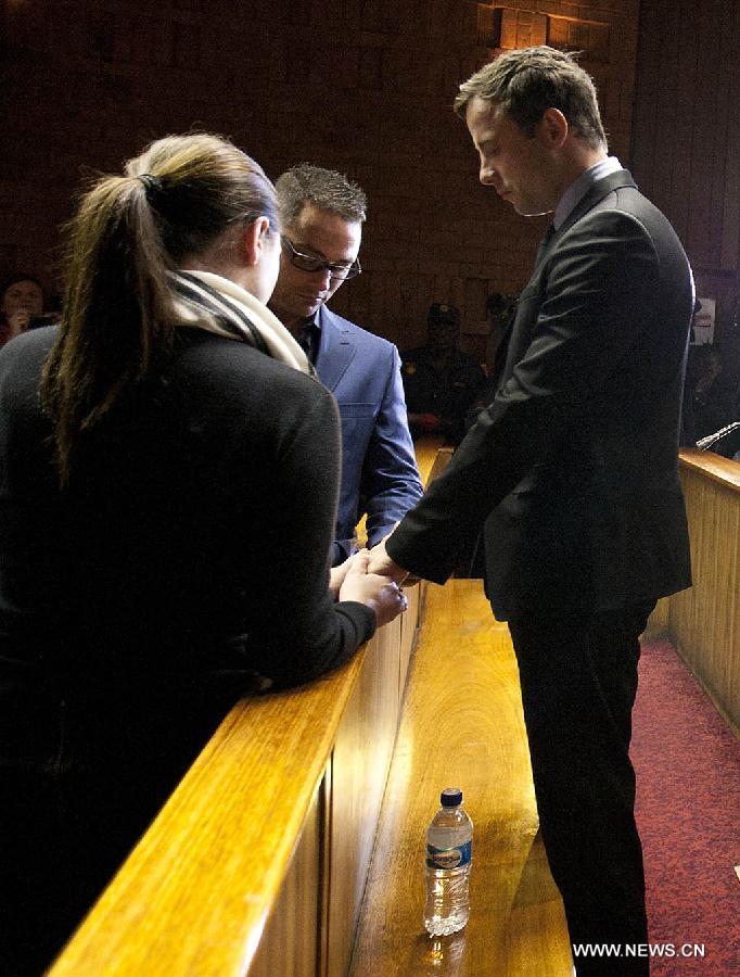 Paralympic running star Oscar Pistorius (R) stands next to his sister Aimee (L) and his brother Carl inside the magistrates court in Pretoria, South Africa, on Aug.19, 2013. (Xinhua/Lali Sadger)