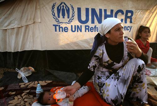 A Syrian-Kurdish refugee feeds her child outside a tent provided by the UNHCR at the Quru Gusik refugee camp on August 27, 2013. More than 50,000 Syrian refugees have crossed into Iraq's Kurdish region in less than two weeks, an official said on August 26, 2013, as authorities rush to house them in more permanent camps. [Xinhua/AFP]
