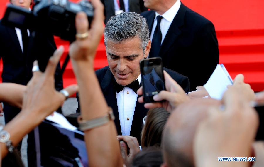 American actor George Clooney signs for fans on the red carpet of the opening ceremony of the 70th edition of Venice Film Festival on lido island, Venice, on August 28, 2013.[Xu Nizhi/Xinhua]