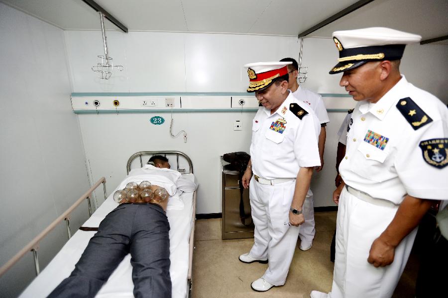 Myanmar officials inspect a patient receiving Chinese traditional treatment on Chinese hospital ship Peace Ark at Thilawa Port in Yangon, Myanmar, Aug. 28, 2013. Chinese hospital ship Peace Ark on Wednesday arrived at Thilawa Port in Yangon at the invitation of Myanmar Navy as part of an overseas voyage to provide medical services to local residents. [Xinhua]