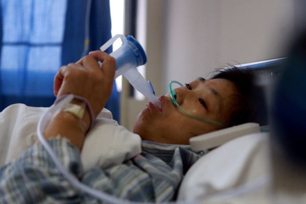 An injured worker receives treatment at a hospital in Baoshan district, Shanghai, on Saturday. Fifteen people were killed and 25 others injured, five critically, after a liquid ammonia leak from a refrigeration unit of Shanghai Weng’s Cold Storage Co on Saturday.[Liu Xin / China Daily]