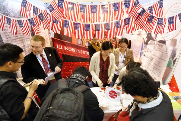 Students and parents ask for information at a college fair in Beijing in March. A report says fewer Chinese students applied to US graduate schools this past year.Xinhua