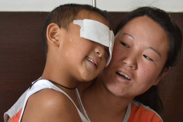 Thank you': In his mother's arms, 6-year-old Guo Bin, whose eyes were gouged out by a woman last week, thanks a man who donated money to him in a hospital in Taiyuan, Shanxi province, on Tuesday. Police identified the boy's aunt, who has committed suicide, as the suspect, though doubts remain. [Hou Liqiang / China Daily]