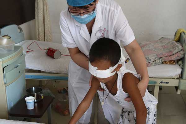 Guo Bin, aided by a doctor at Shanxi Eye Hospital in Taiyuan, tries to walk during a rehabilitation training program that started on Sunday.[China News Service] 