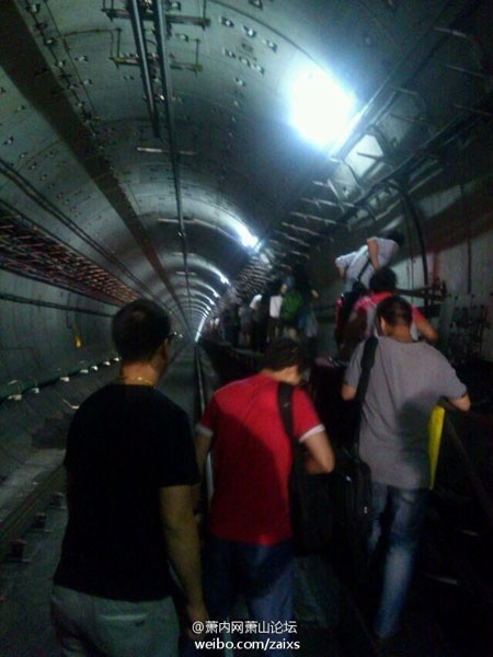 Passengers walk through an emergency passageway as the train was evacuated on Sunday, September 9, 2013. A train running on Hangzhou subway's line one powered down in the tunnel-way that travels under the Qiantangjiang river. [Photo: weibo.com]